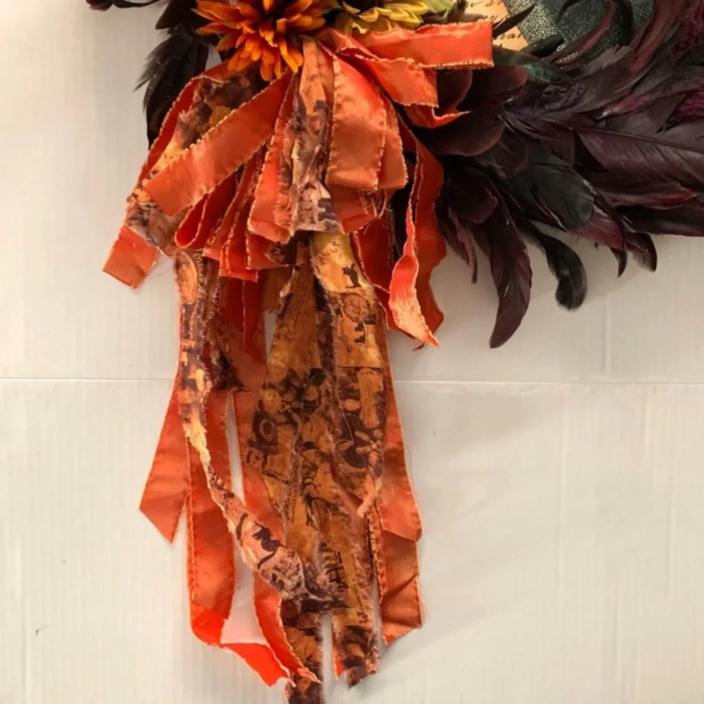 Dark red and black feather wreath with fall floral and a crowned crow center